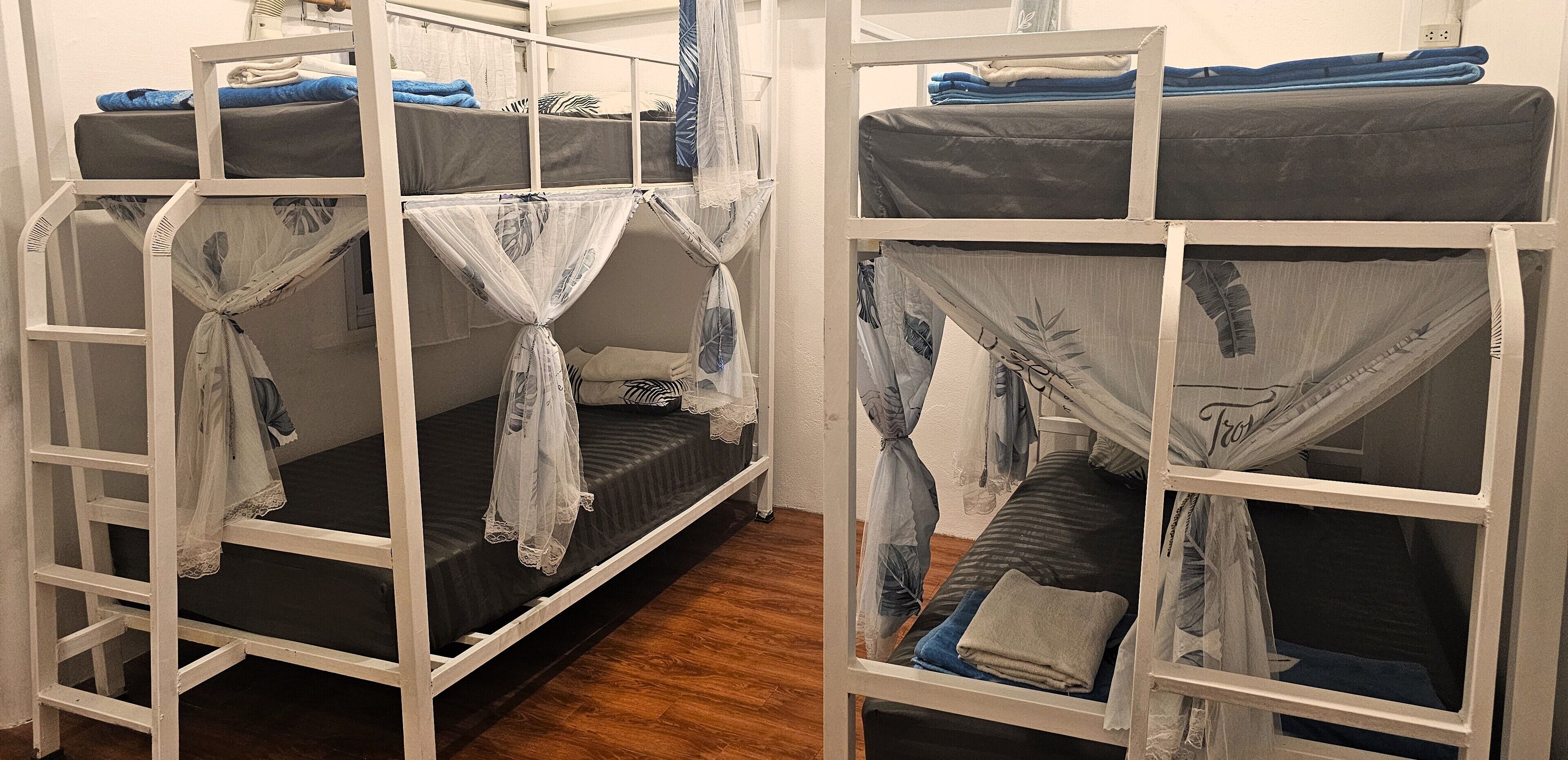 A dormitory room with bunk beds, each with a mosquito net.