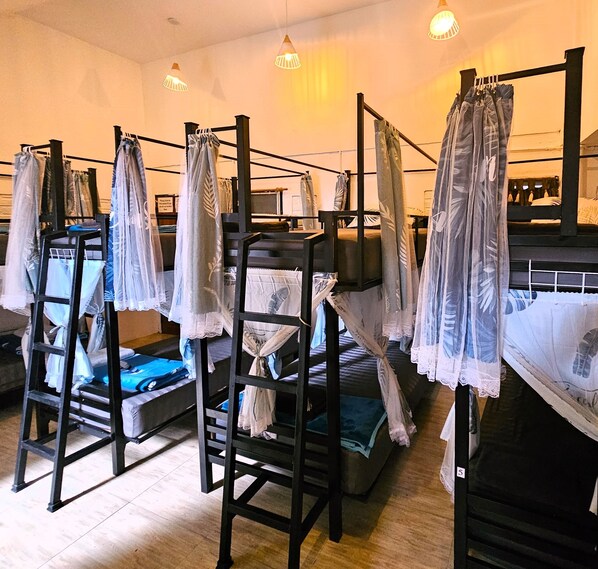 Bunk beds with curtains, wooden floors, and hanging lights. - Hideout Hostel (Ko Pha-ngan)