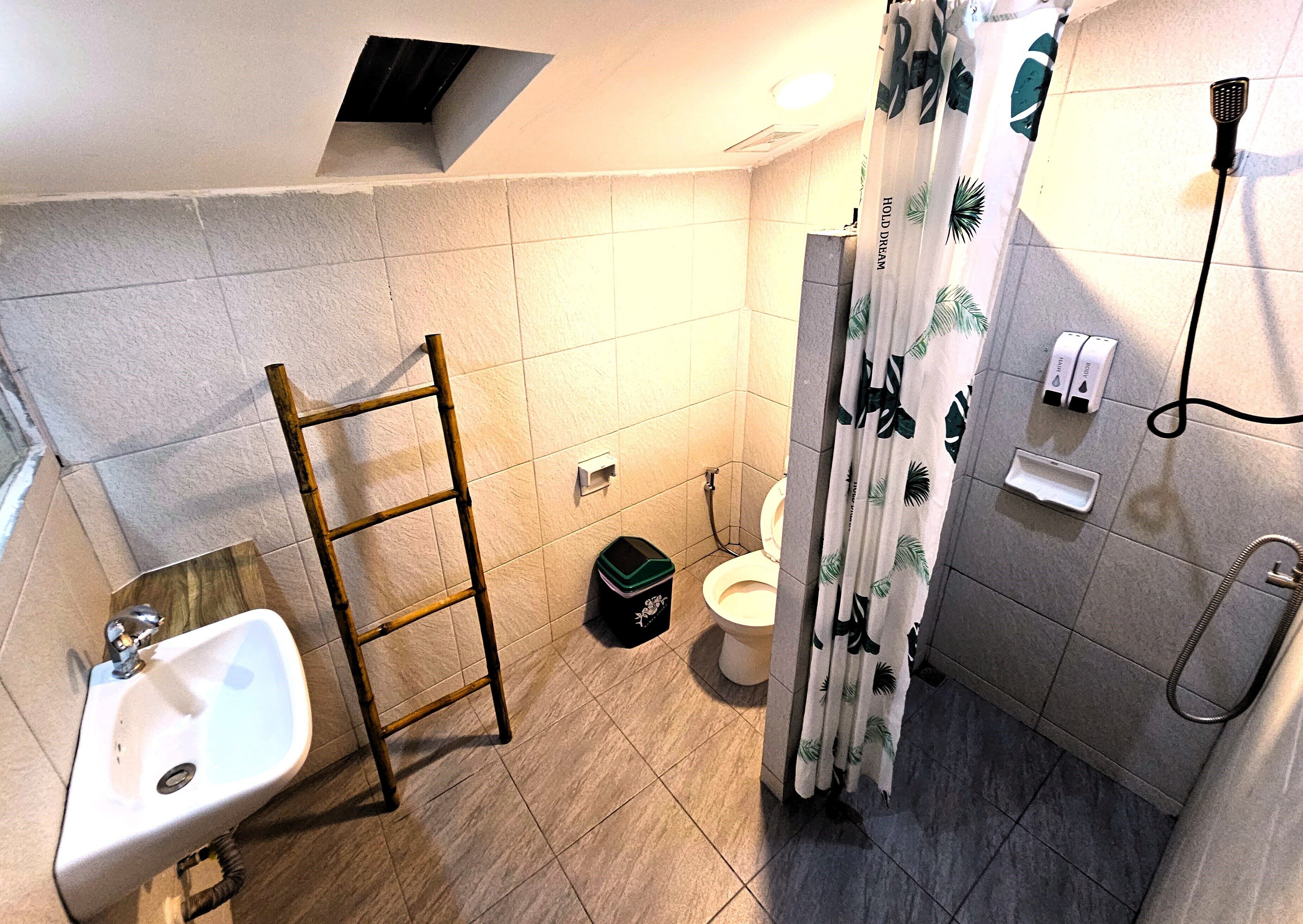 Un baño con lavamanos, inodoro, ducha y una escalera.