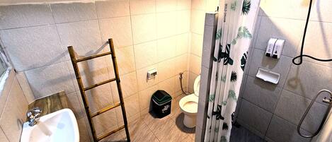 Un baño con lavamanos, inodoro, ducha y una escalera.