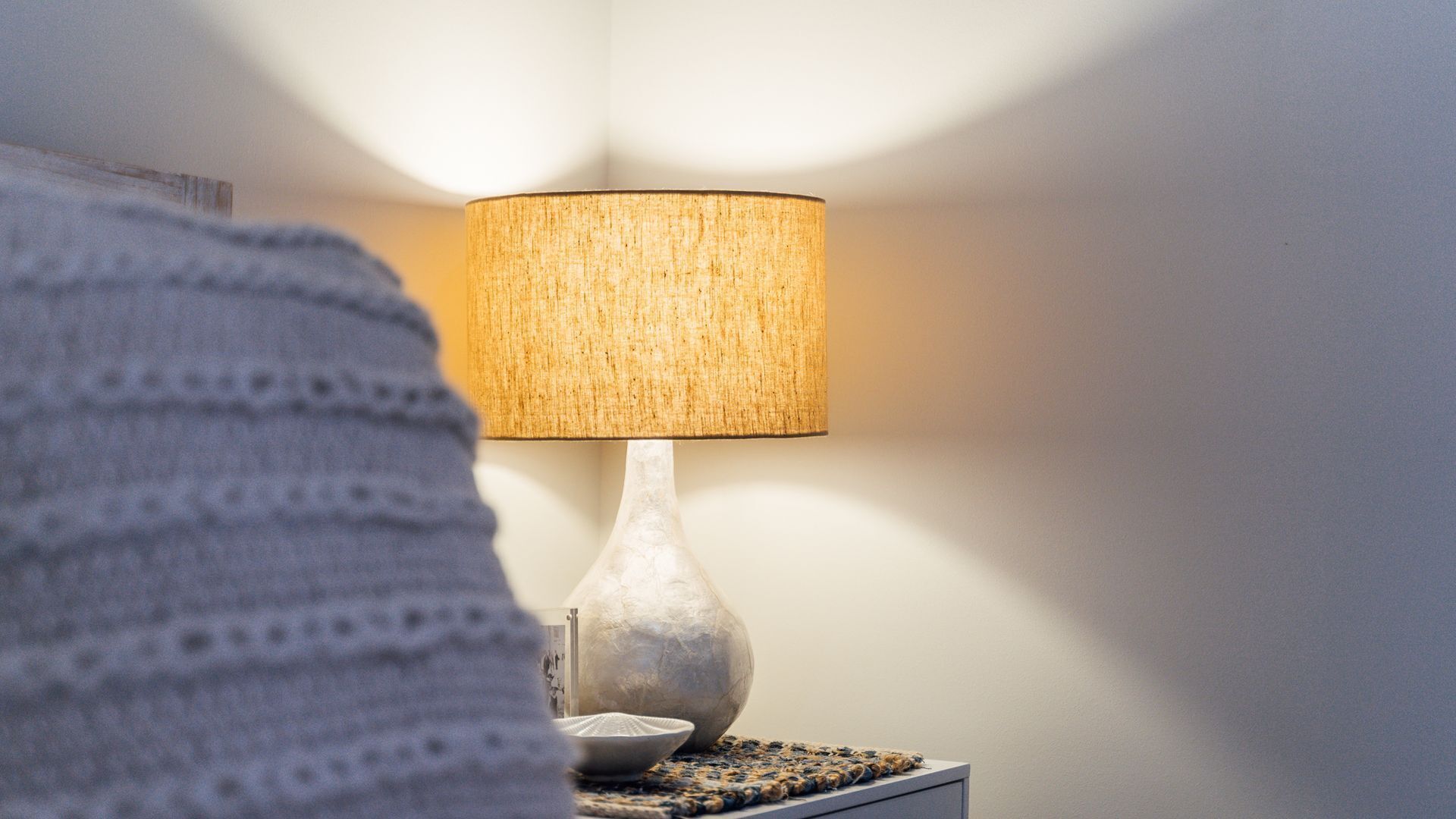 Une lampe avec un abat-jour texturé, posée sur une table de chevet.