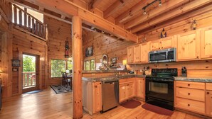 A wooden cabin with a kitchen featuring a microwave, stove, and wooden cabinets.