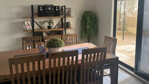 A dining area with a wooden table and chairs, surrounded by shelves with books and decorative items.