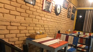 Een restaurant met bakstenen muren, houten banken en een tafel met een strepen tafelkleed.