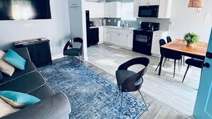 A modern living room with a sofa, chairs, and a dining area with a table and chairs. - ATL: 6BR Triplex—Chic, Boho,Retro Vibes |Sleeps 16 (Atlanta)