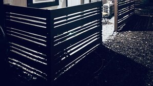 Et toetagers hus med træfacade, en veranda med bænk og lyskæder.