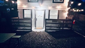 En toetagers bygning med en fordør og to vinduer. Der er en bænk foran bygningen.