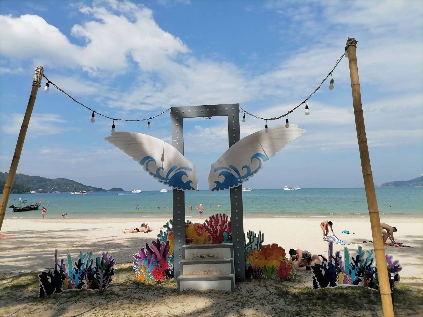 A beach with a decorative archway featuring colorful coral decorations and string lights.
