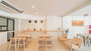 A modern meeting room with a long table, several chairs, a small plant, and a clock on the wall.