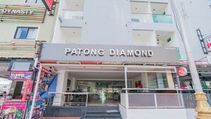 Exterior do hotel Patong Diamond, com entrada clara, escadaria que leva à entrada e placa visível.