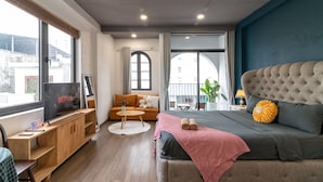 Una habitación de hotel moderna con una cama grande, un sofá, un televisor y una mesita.