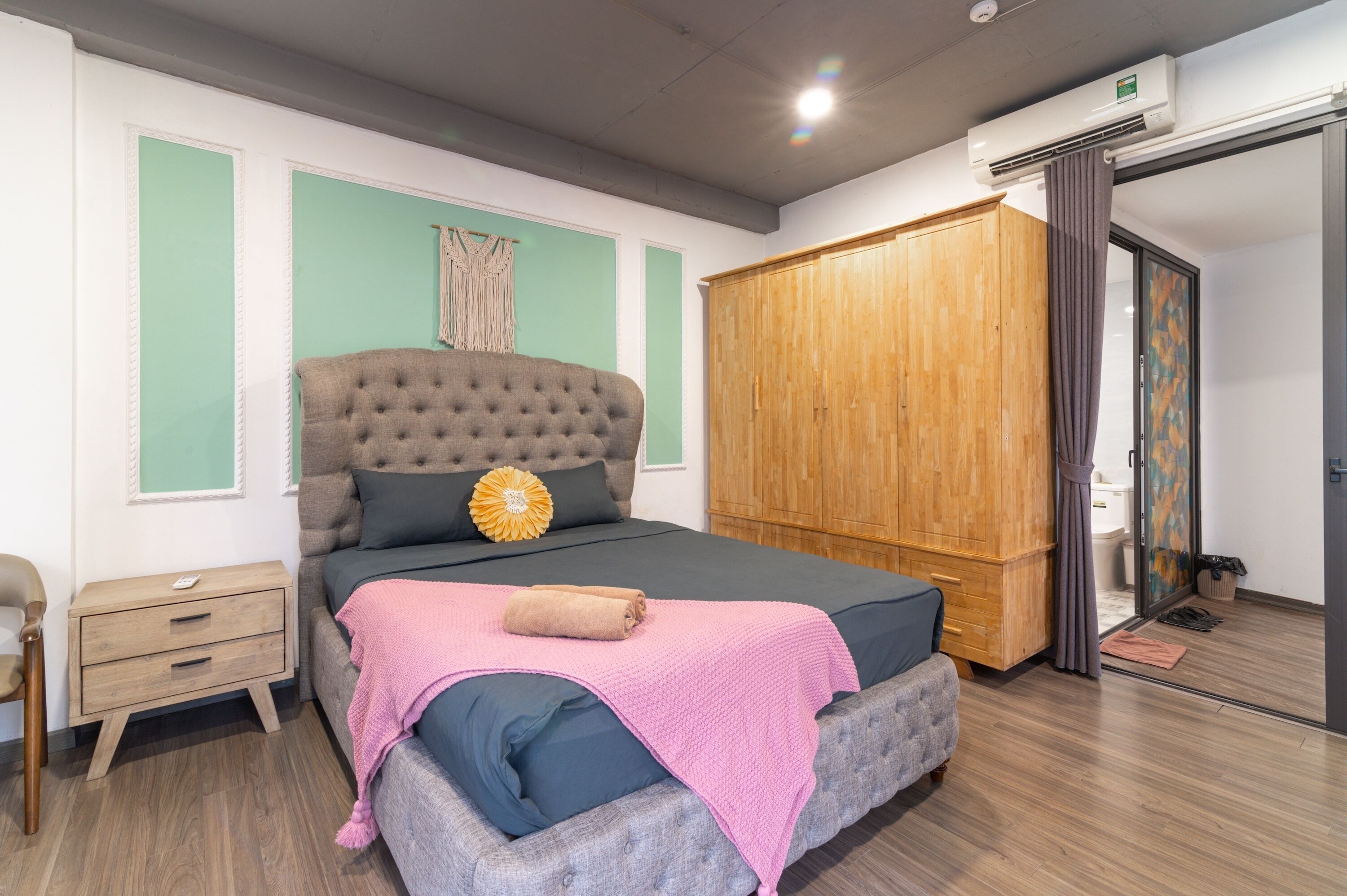 A bedroom with a large bed, a wooden wardrobe, a nightstand, and a window with curtains.