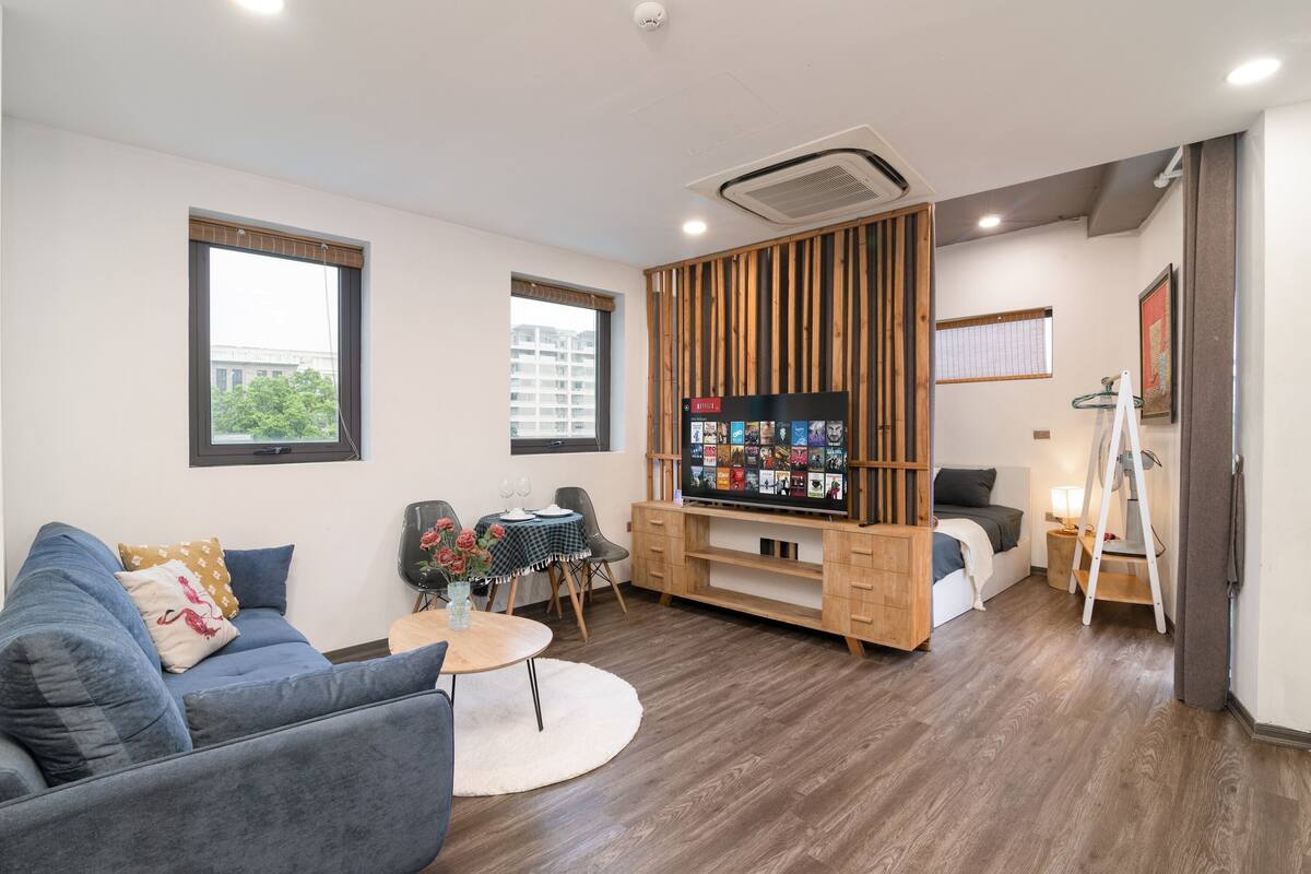 A modern living room with a sofa, a coffee table, a TV, and a small dining area.