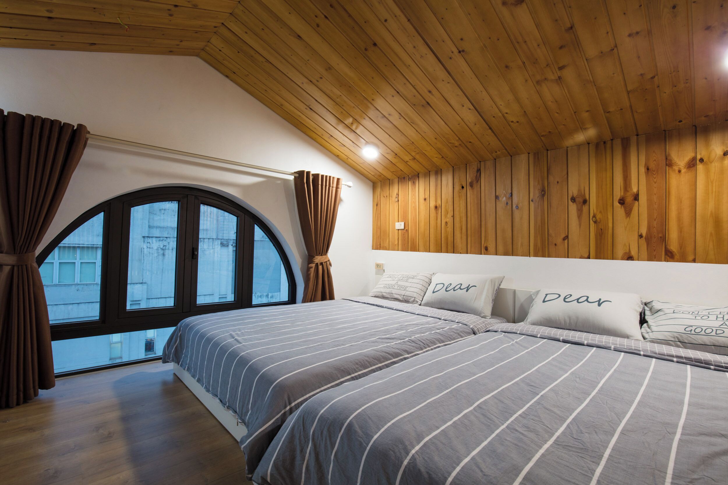 Une chambre avec un grand lit, un plafond en bois et une fenêtre avec des rideaux.