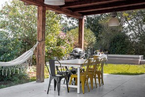 An outdoor patio with a wooden pergola, a table with chairs, and a grill. - Artistic Vac Villa w pool by Sea N' Rent (Rishon LeTsiyon)