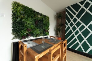 A dining area with a wooden table, two chairs, and a green vertical garden wall. - Lovely 2-bed Apartment in Blackpool Secret House (Blackpool)