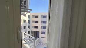 Ein Fenster mit Blick auf ein Mehrstöckige Gebäude und einen Poolbereich.