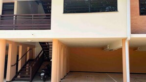 Ein zweistöckiges Gebäude mit einer Treppe zum Obergeschoss, einem Balkon und einem abgestellten Motorrad.