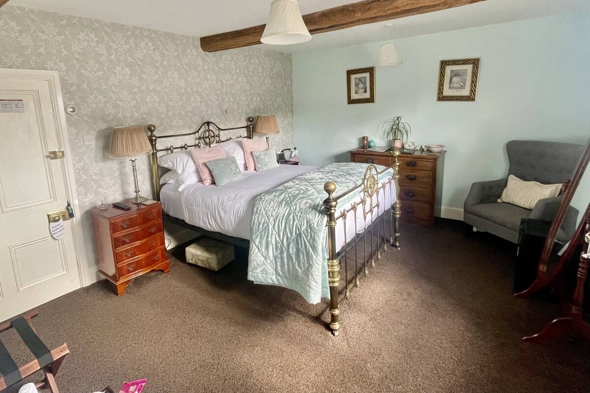A bedroom with a bed, bedside tables, a dresser, a chair, and a door.