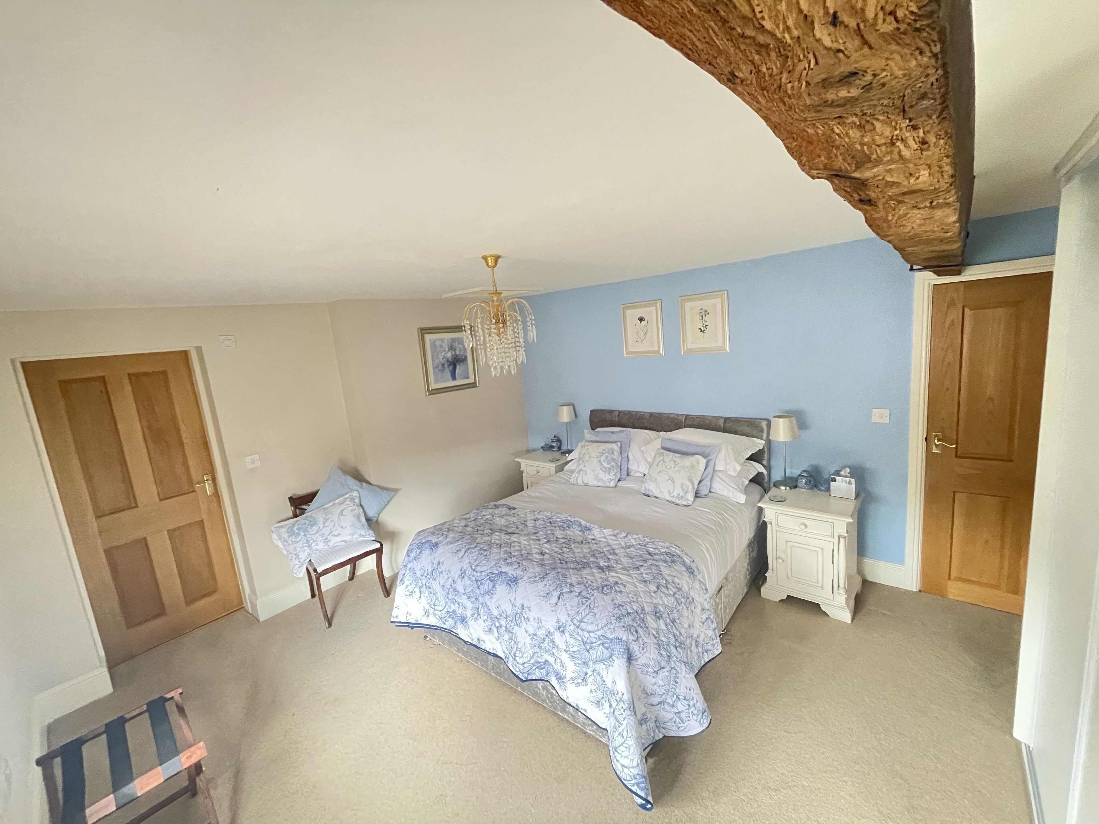 A bedroom with a large bed, two bedside tables, a chair, and a wooden door.