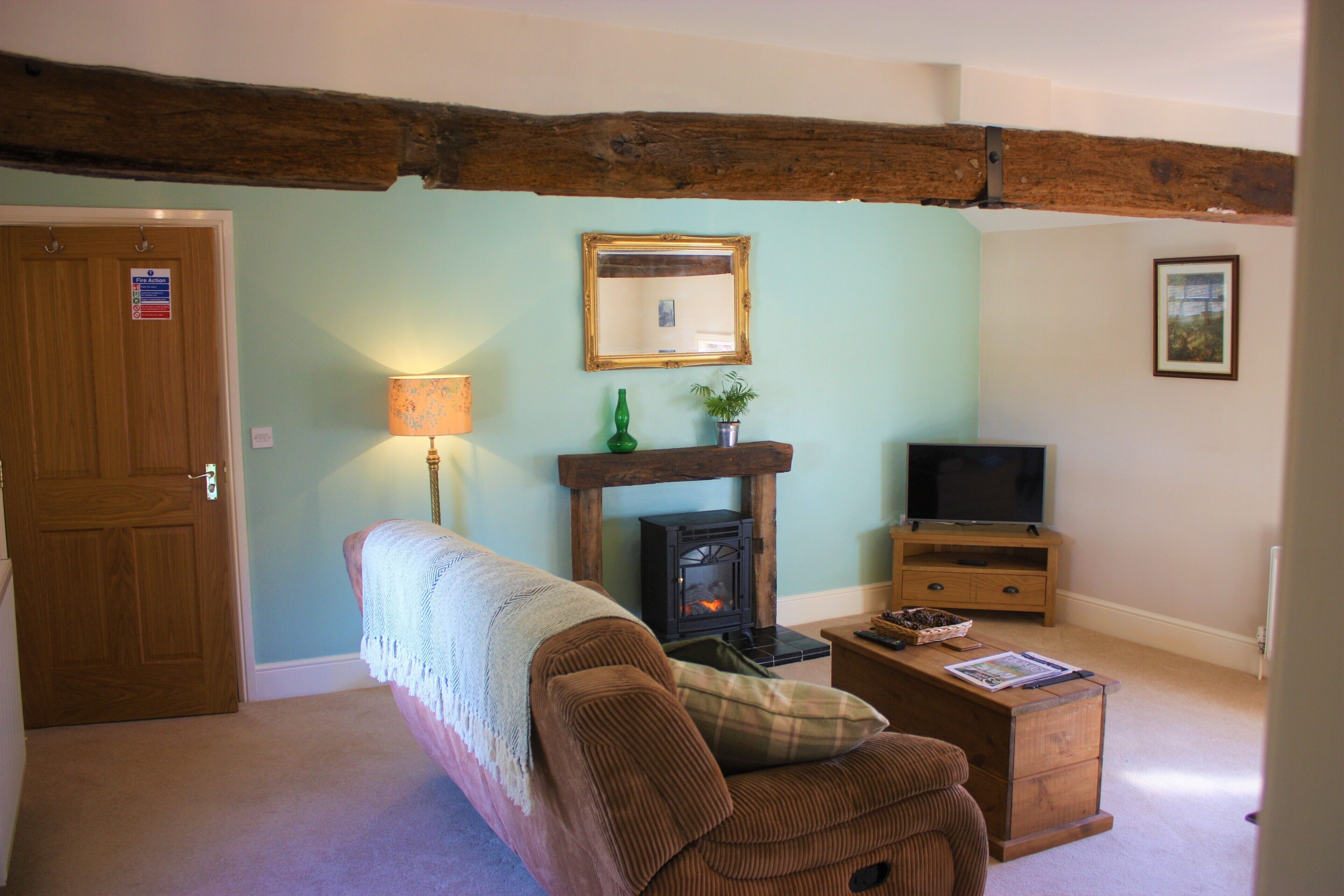 A cozy living room with a wooden bench, a fireplace, a television, and a door with a sign.