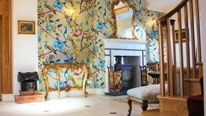 A room with a floral wallpaper, a fireplace, a wooden staircase, and a table with a vase. - Eagle House- Award Winning B&B and Apartment (Stafford)