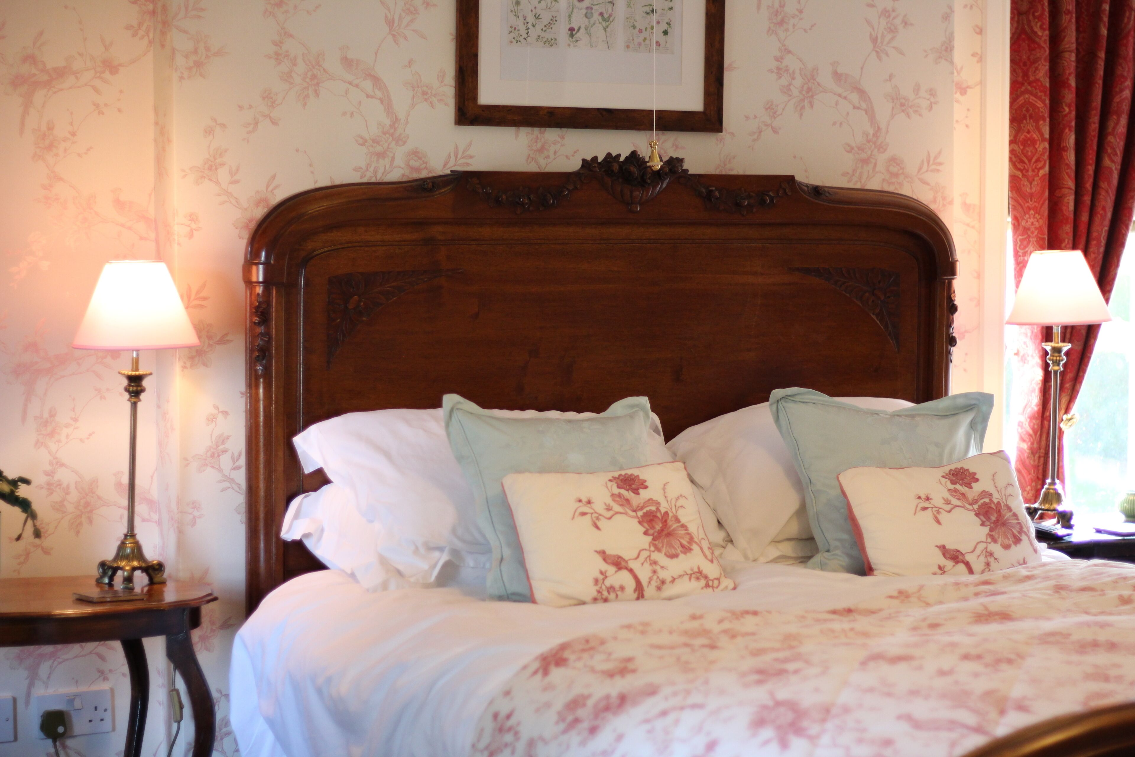 A bedroom with a wooden headboard, floral-patterned bedding, and two bedside lamps.