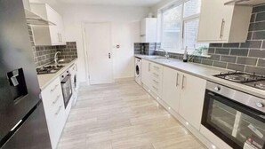 A modern kitchen with white cabinets, a stainless steel range, and a large window. - Modern Room in Centrally Located- Room 4 (London)