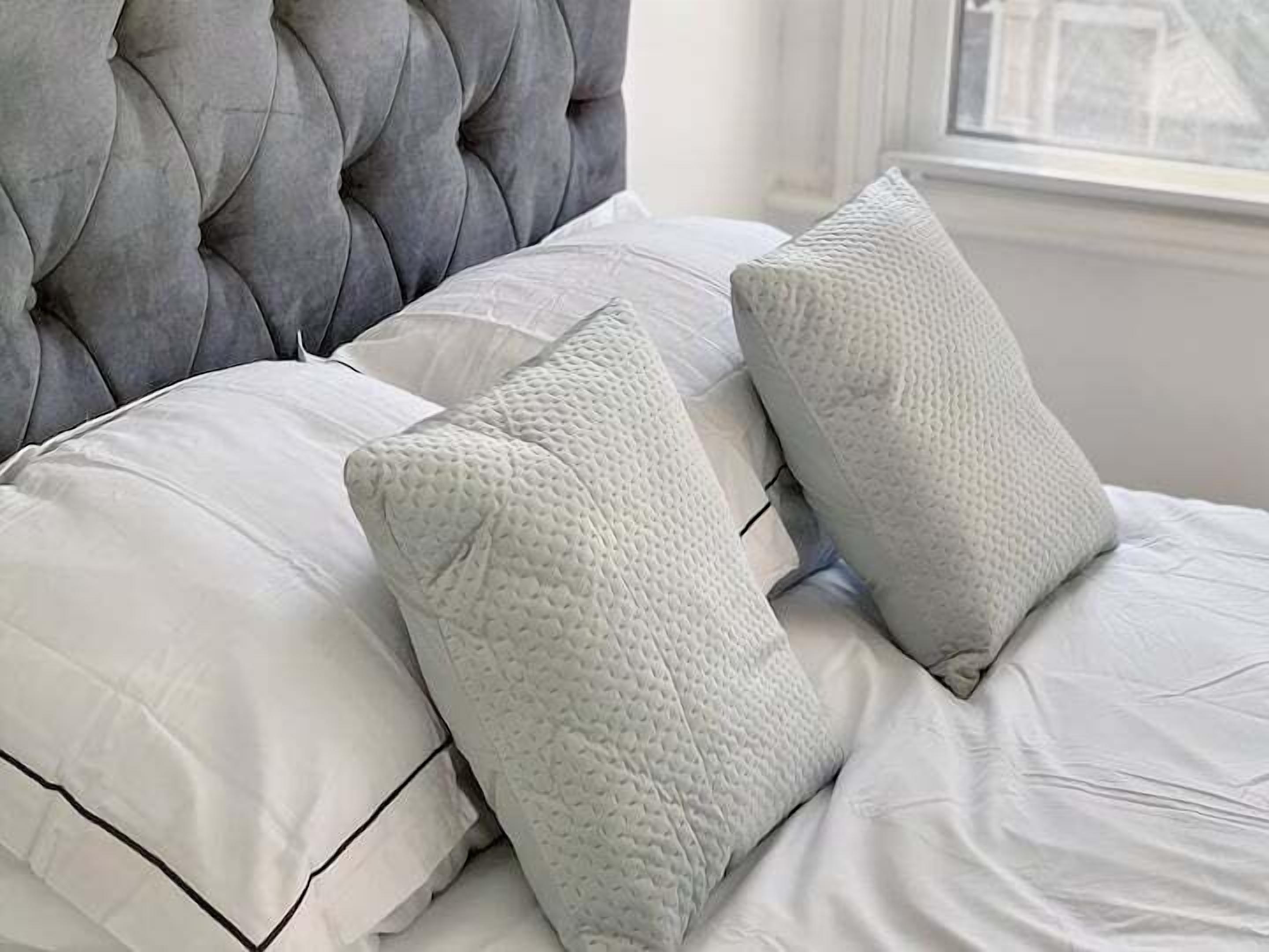 Cama com cabeceira estofada e duas almofadas.