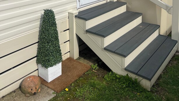 A mobile home with a front door, a small front porch with steps, and a potted plant on the porch. - Lovely 2-bed Cabin in Birchington (Birchington)