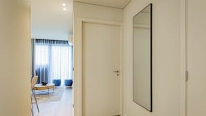 A hallway with a white door, a large mirror, and a dining area with a table and chairs.