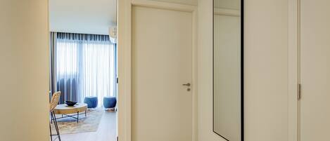 Un couloir avec une porte blanche, un grand miroir et un coin repas comprenant une table et des chaises.