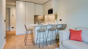 A modern kitchen with a central island, bar stools, and a built-in oven.