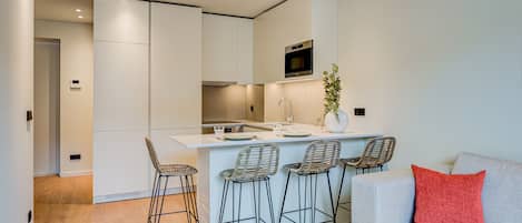 Una cocina moderna con una isla central, taburetes de bar y un horno empotrado.