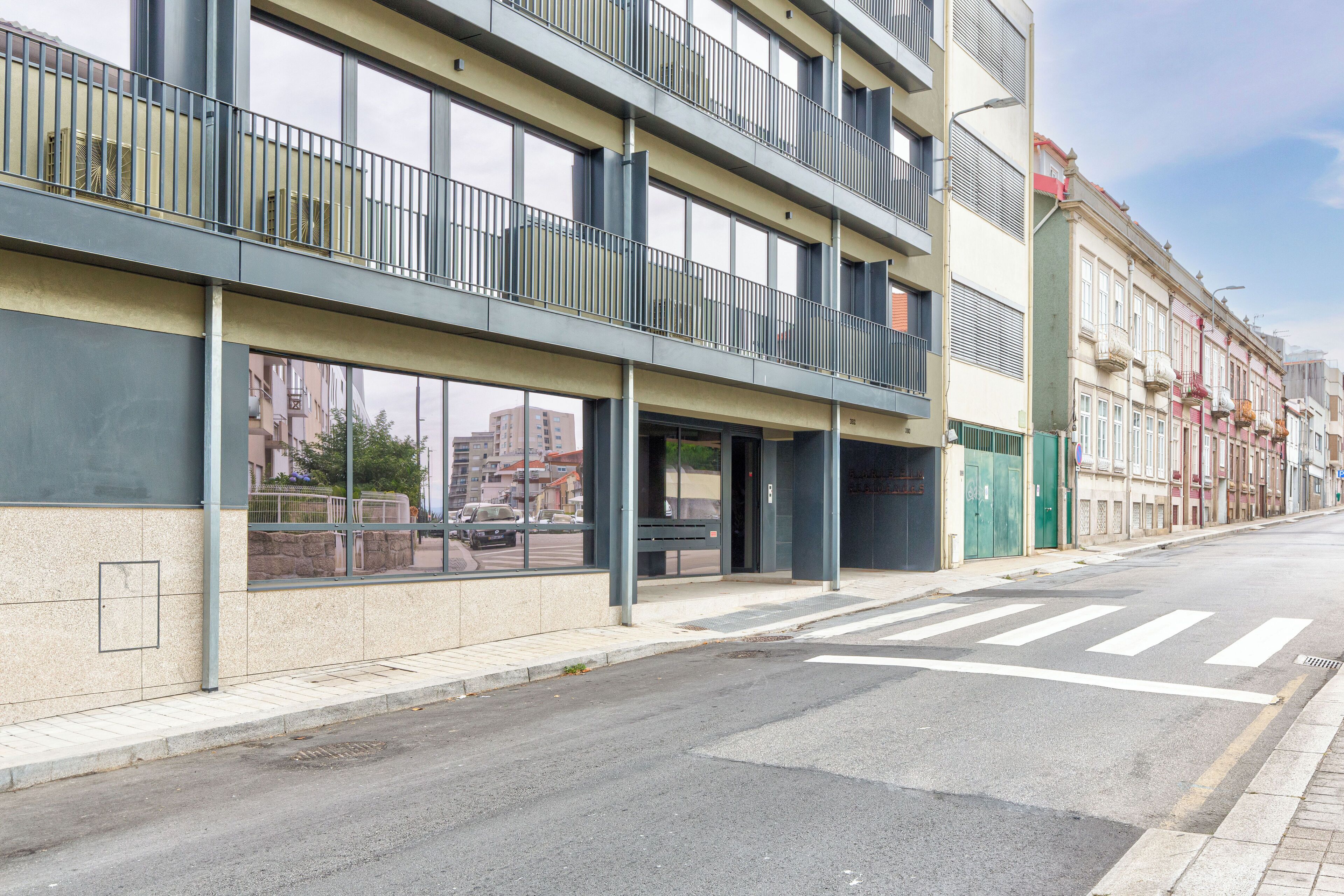 A modern building with large windows, a flat facade, and a pedestrian crossing.