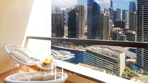 Ein Balkon mit Blick auf die Stadt, Korbstühle, ein kleiner Tisch mit einem Getränk und eine Glaskugel.