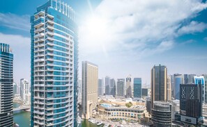 A high-rise hotel with multiple balconies, a marina with boats, and a clear view of the surrounding cityscape.