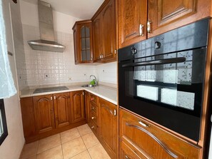A kitchen with wooden cabinets, a stainless steel range hood, and a black oven.