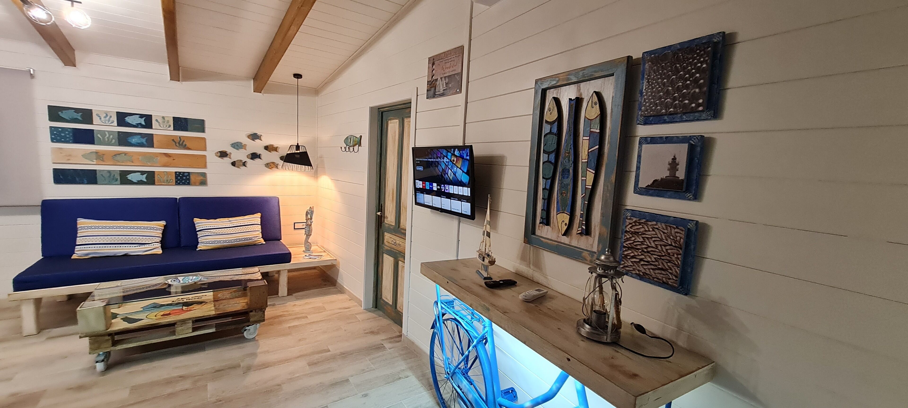 A cozy living room with a blue sofa, wooden coffee table, and wall art.