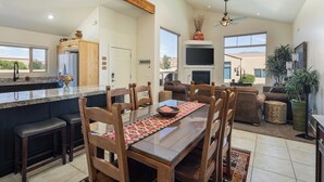 Una cocina amplia con encimera de granito, sillas de madera y una mesa de comedor para cuatro.