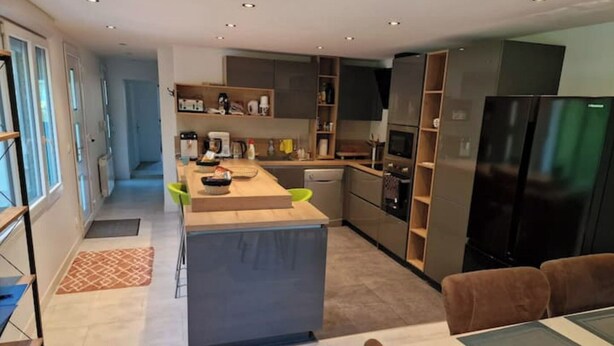 A modern kitchen with a central island, built-in appliances, and a dining area with a sofa and table.