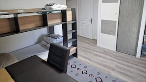 A compact room with a bunk bed, a desk, and a wardrobe.