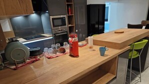 A modern kitchen with a wooden countertop, built-in appliances, and a dining area with a table and chairs.