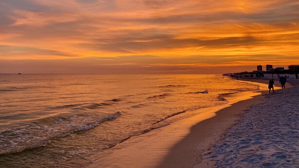 A beach scene with a sunset, waves, and a pier with people walking. - Best View in Ft Morgan | Relaxing Retreat w Pool - Boat Slips + Hot Tub (Gulf Shores)