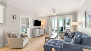 A modern living room with a grey sofa, a beige armchair, and a wooden coffee table. - Best View in Ft Morgan | Relaxing Retreat w Pool - Boat Slips + Hot Tub (Gulf Shores)