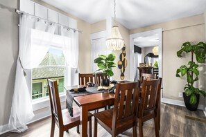 A dining area with a wooden table and chairs, a chandelier, and potted plants. - Boho 3BR Near Mercedes-Benz Stadium & BeltLine | Pet-Friendly (Atlanta)