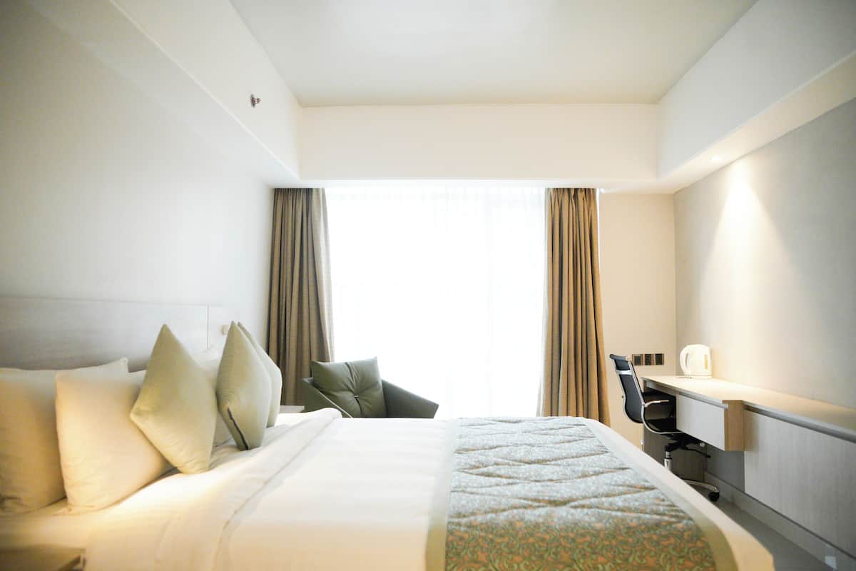 A hotel room with a bed, a desk, and a chair.