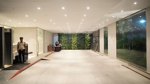 Un interior moderno con una pared de vidrio, un mostrador de recepción y una persona con uniforme de pie.