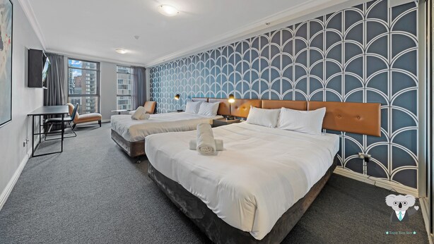 A hotel room with two beds, a desk, and a chair. - KozyGuru | Sydney CBD | 2 Bed Studio (Haymarket)