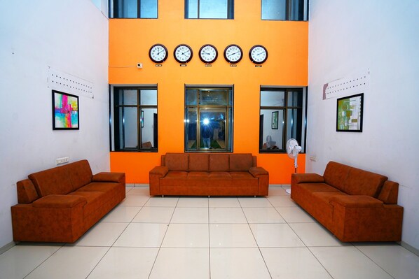 A lobby with two sofas, a large window, and five wall clocks.